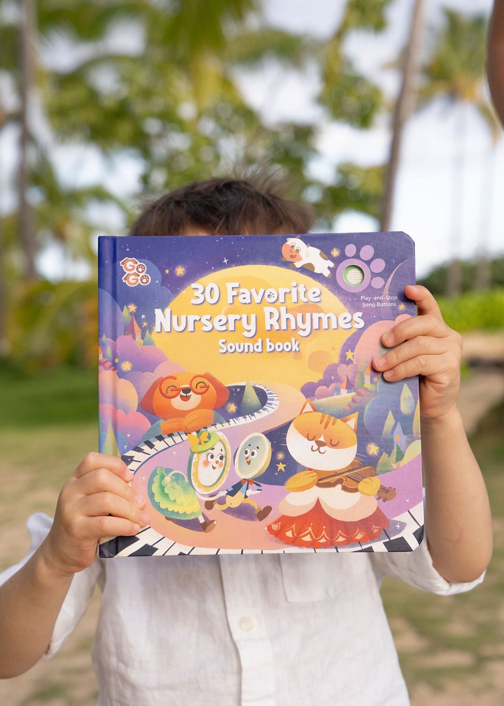 A child holding a Go Go Fun Learning singing sound book outdoors
