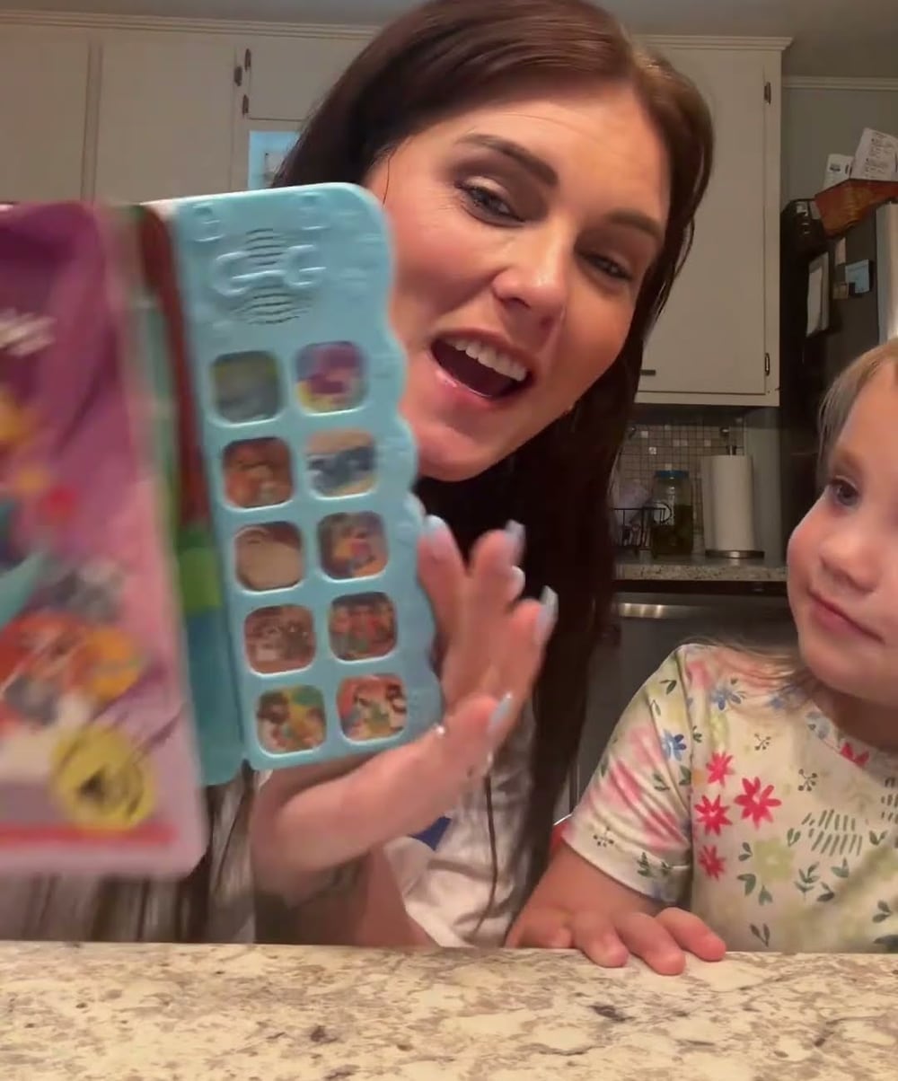 A caregiver and young child sharing a Go Go Fun Learning Christian sound book at home