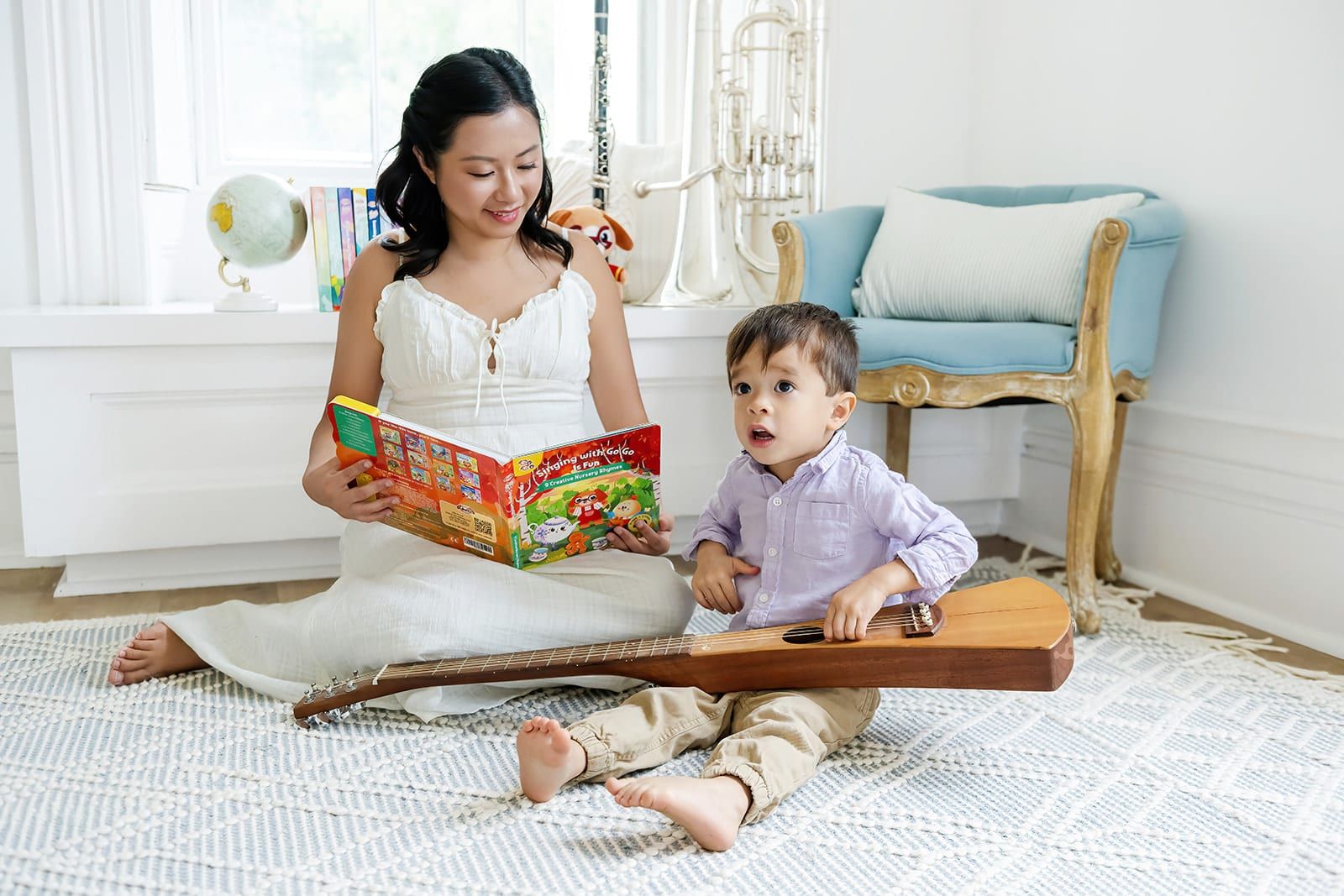A mom reading a Go Go Fun Learning sound book with her toddler on the rug, guitar between them